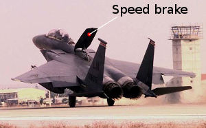 An F-15E Strike Eagle jet fighter airplane raises its aerodynamic speed brake to slow down as it comes into land.