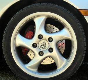 A closeup of a Porsche sports car front wheel showing the brake disk behind